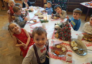 Dzieci siedzą przy świątecznym, wigilijnym stole. Kosztują tradycyjne potrawy przygotowane przez nasze Panie Kucharki.